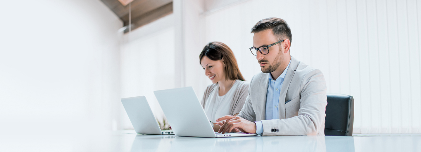 Two administrators are managing devices using LG SuperSign Control+ on personal PCs.